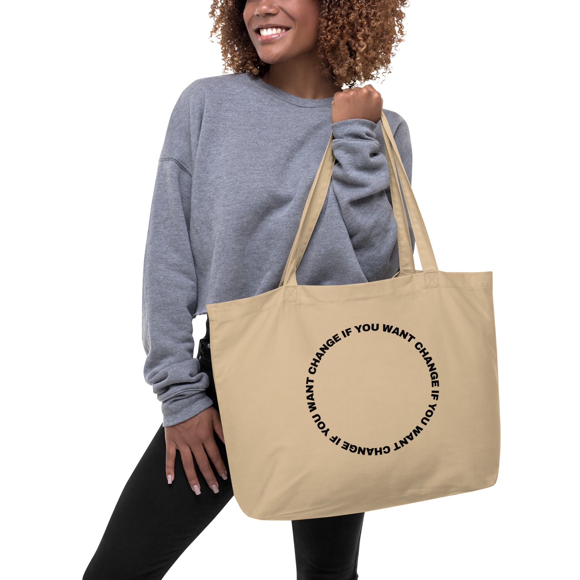 Organic cotton tote bag with black circular quote design, carried over the shoulder