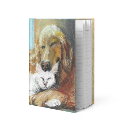 Close-up of matte journal cover with pastel dog and cat illustration — lined cream pages visible, flexible spine